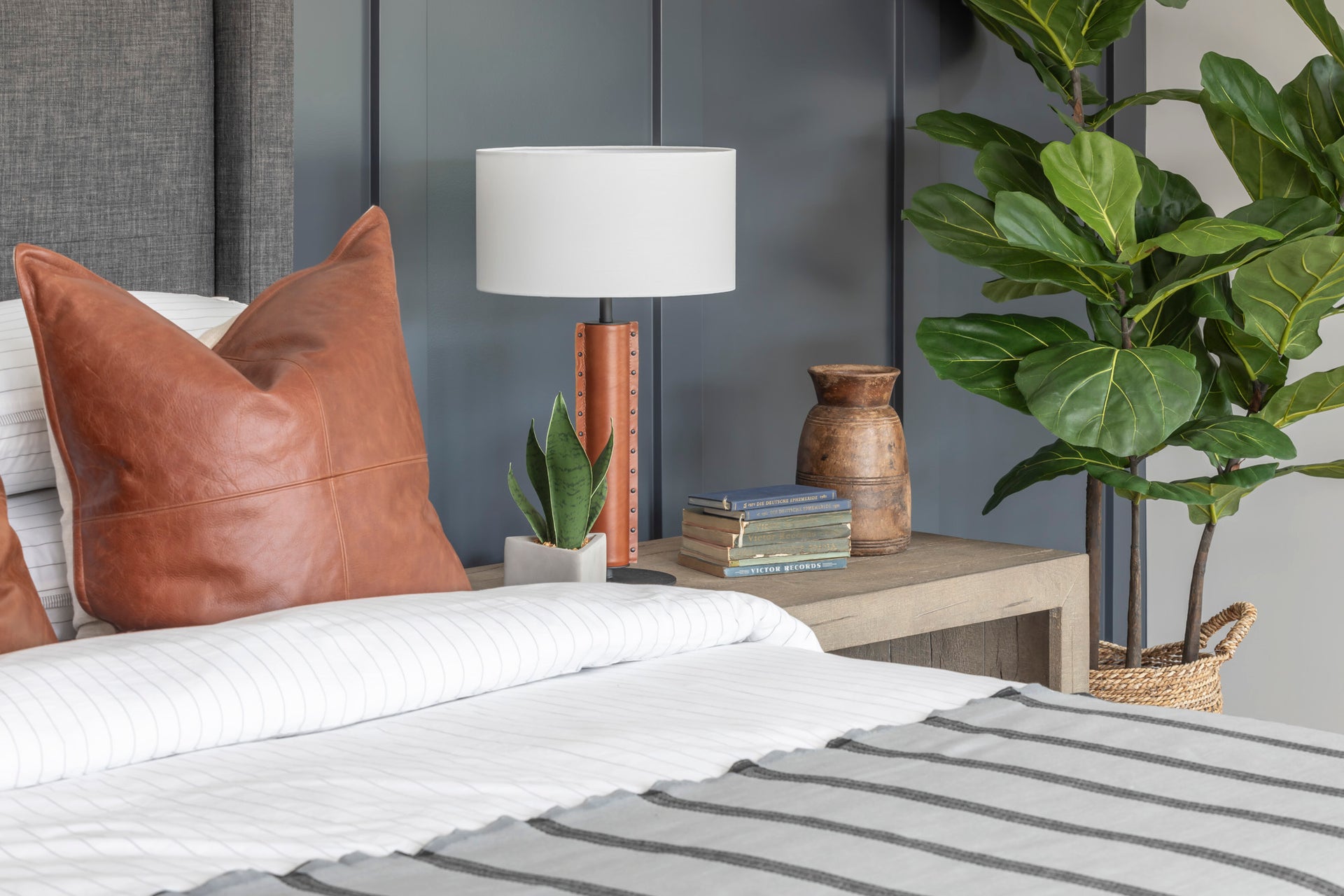 Stylish bed with striped bedding and leather throw pillows