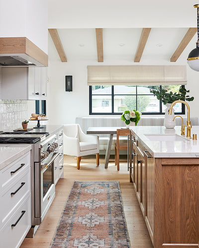 Eclectic open kitchen with white cabinetry and wood island