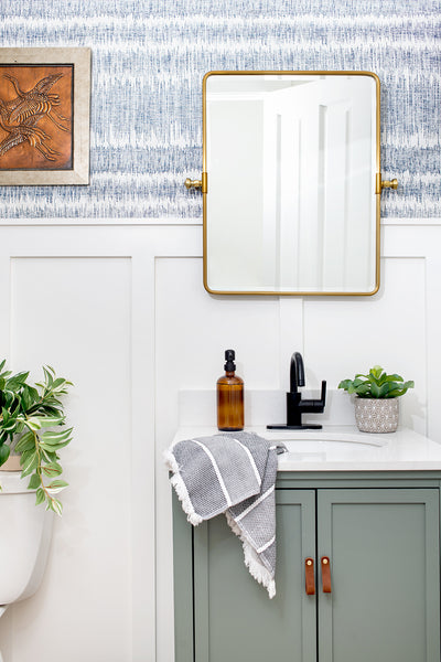 bathroom with green vanity and gold mirror