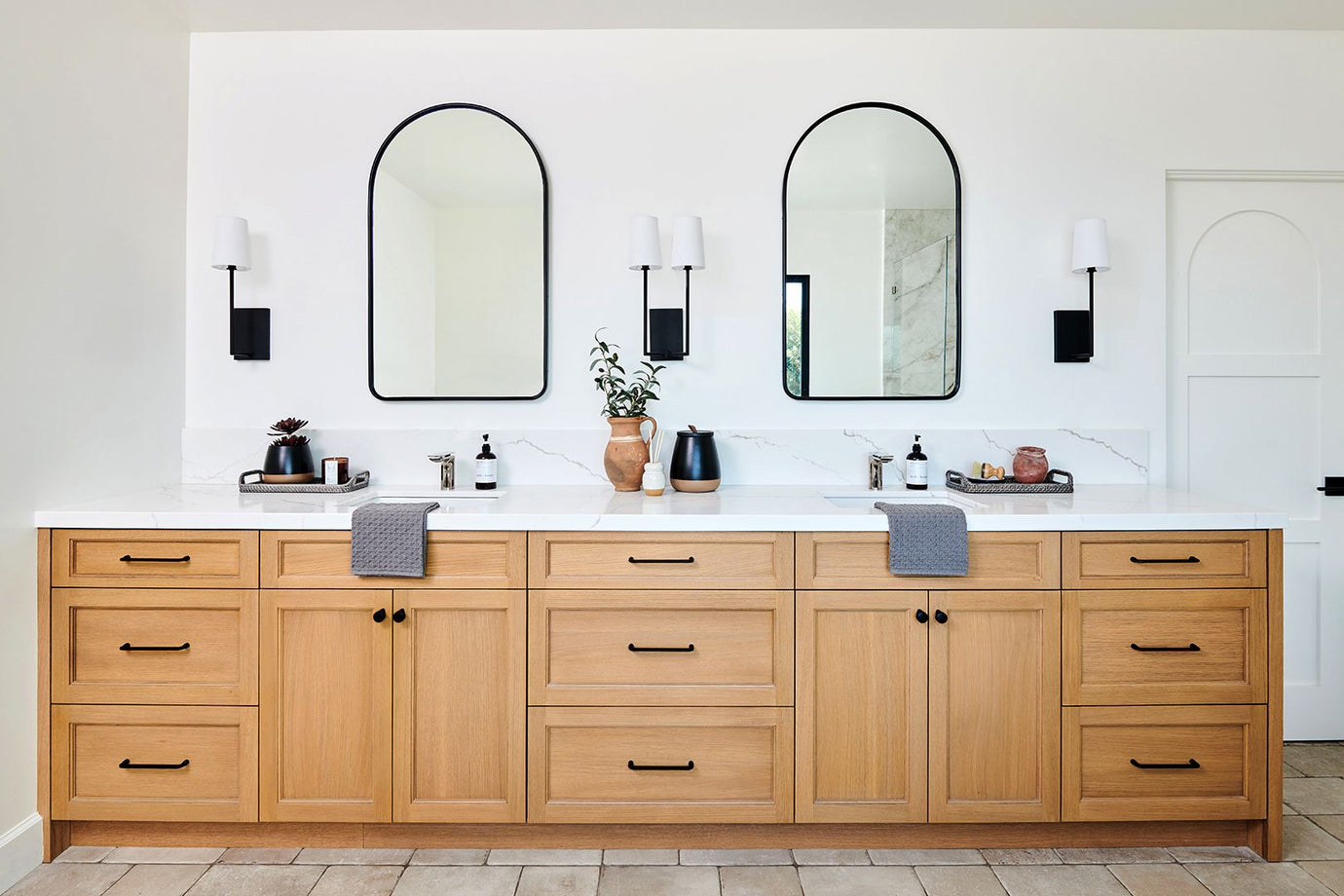 beautiful bathroom with wood cabinetry  and ached mirrors