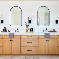Sleek yet warm bathroom with arched mirrors, modern light fixtures and white oak vanity