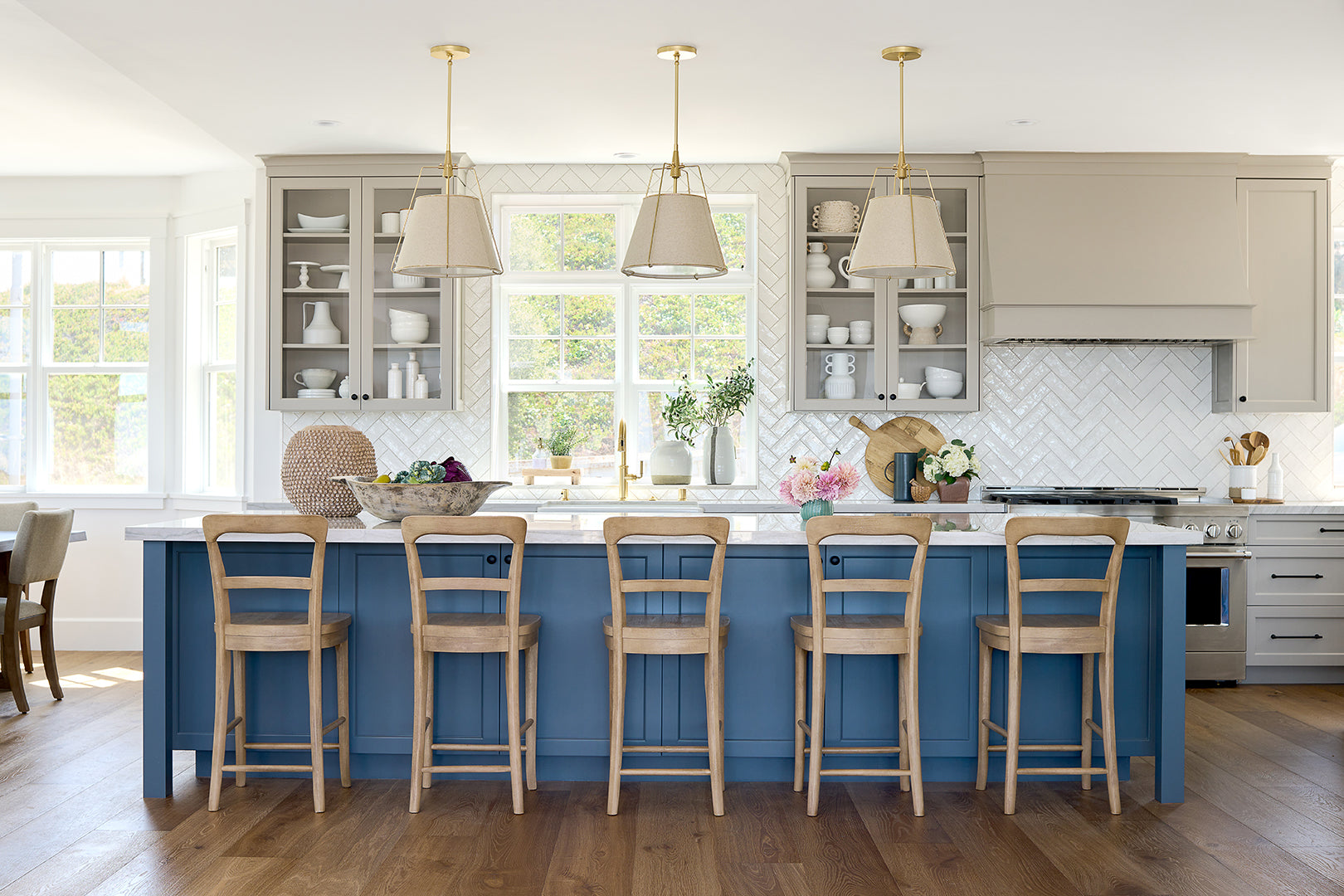 Beautiful  cream and white kitchen with large bright blue  island with 5 barstools