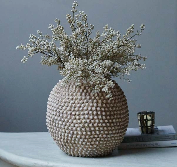 Large textured vase with small white flowers in it