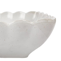 White ceramic bowl with scalloped edge on a white background