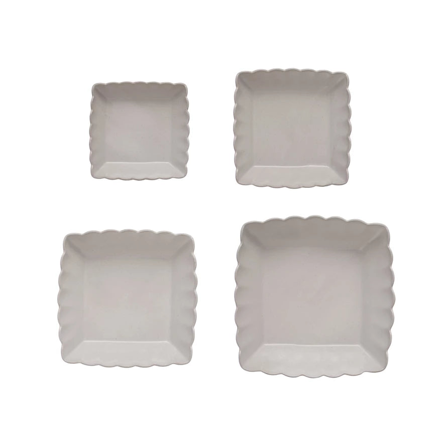 Four square, scalloped-edge plates on a white background