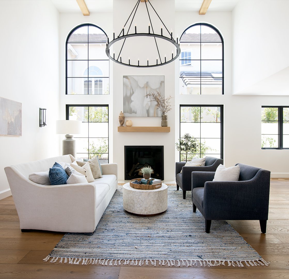 Open livinroom with white couch, arched windows and large circular chandelier