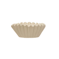 Beige ceramic bowl with ribbed texture on a white background