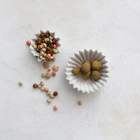 Two white bowls filled with small fruits on a light gray surface