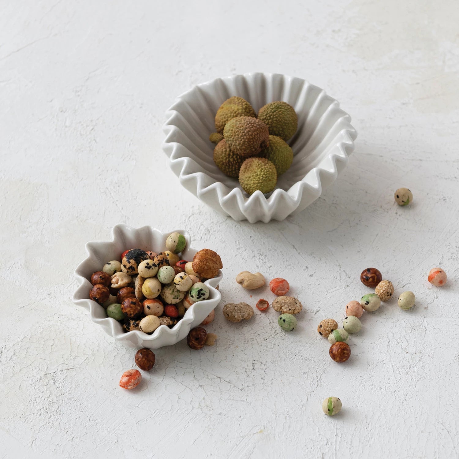 Two ceramic bowls with lychees on a light gray surface