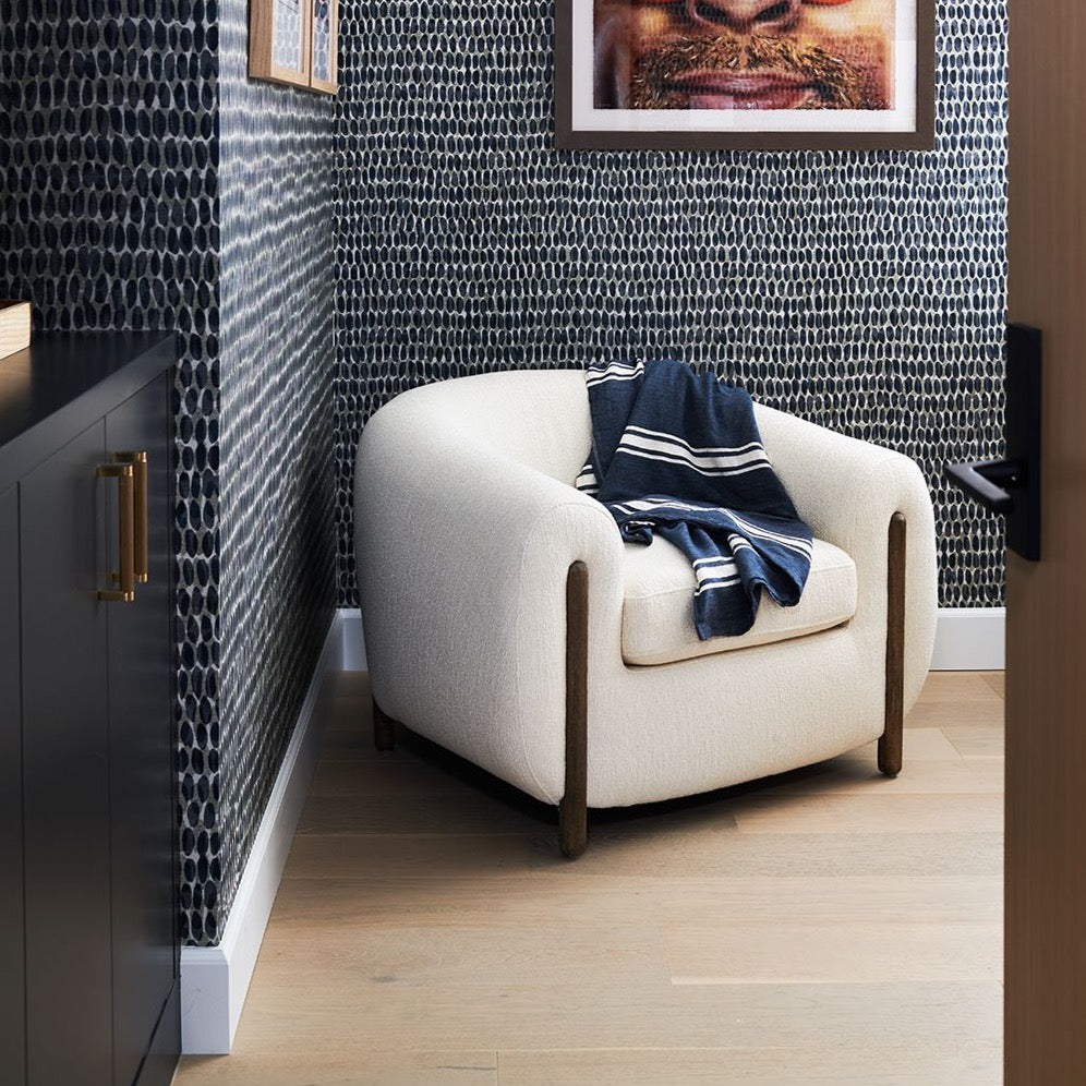White chair with navy throw blanket and modern wallpaper 