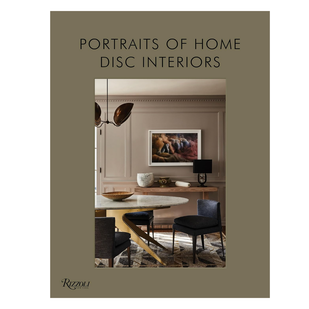 Book cover featuring a photo of a dining room with a round table, four chairs, modern light fixture, artwork on the wall, and decorative items, titled "Portraits of Home Disc Interiors.