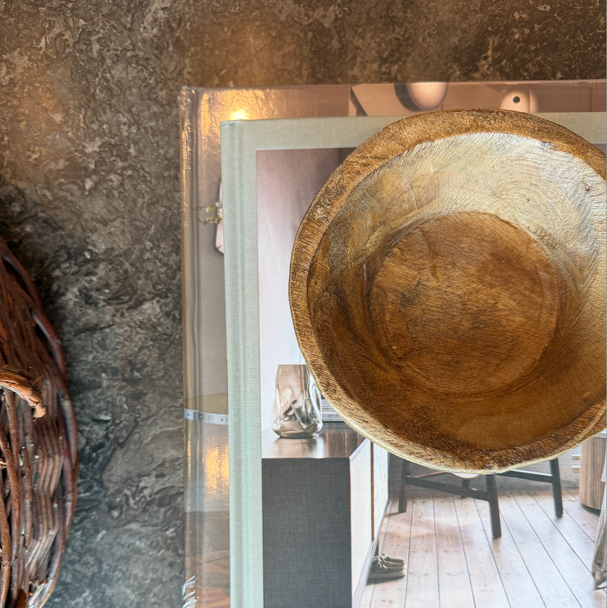 Wooden bowl on a marble surface and stack of books with a blurred indoor background