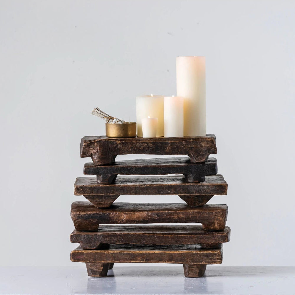 6 stacked wooden pedestals with candles sitting on the top one with a white background