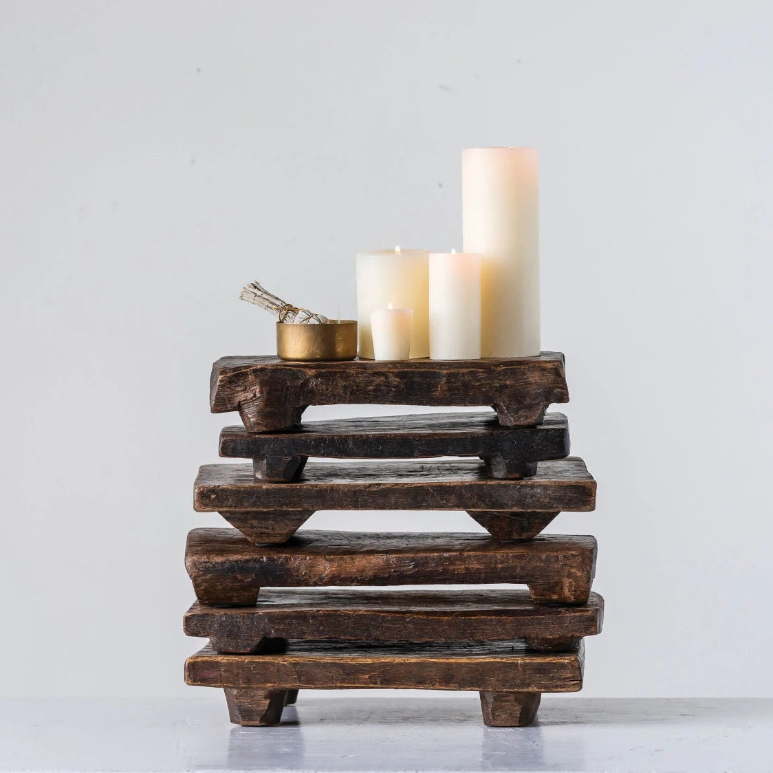 6 stacked wooden pedestals with candles sitting on the top one with a white background